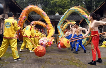 Volunteers perform dragon and lion dance for villagers in SW China's Sichuan